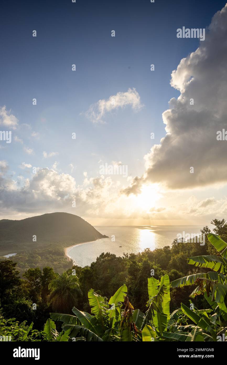 View from a mountain onto an empty sandy beach, the turquoise-coloured sea and the surrounding landscape. The evening sun illuminates the natural Stock Photo