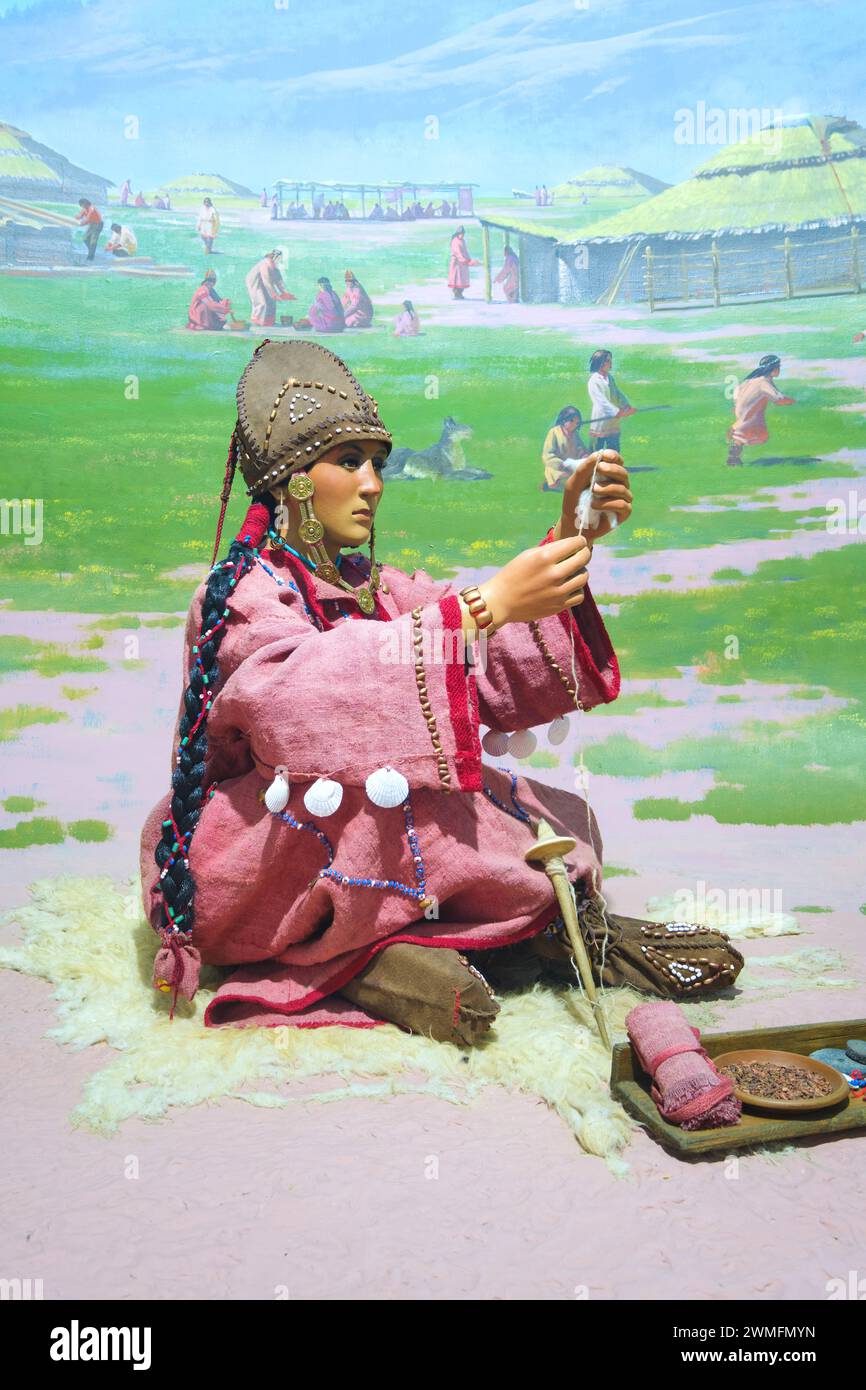 A diorama, recreating a rural, old, traditional scene of a woman sitting in a village, spinning wool or cotton. At the Almaty Museum of Local History Stock Photo