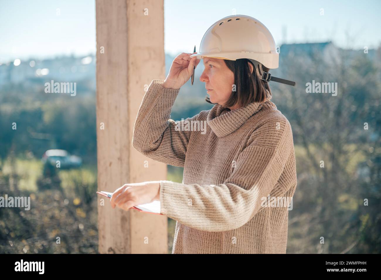 Female architect making notes and remarks during building site inspection, selective focus Stock Photo