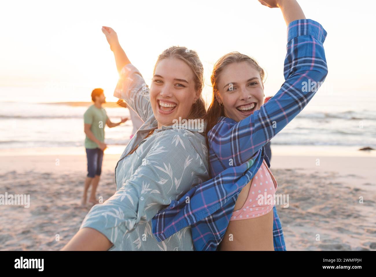 Two young Caucasian women are enjoying a beach sunset, with copy space Stock Photo