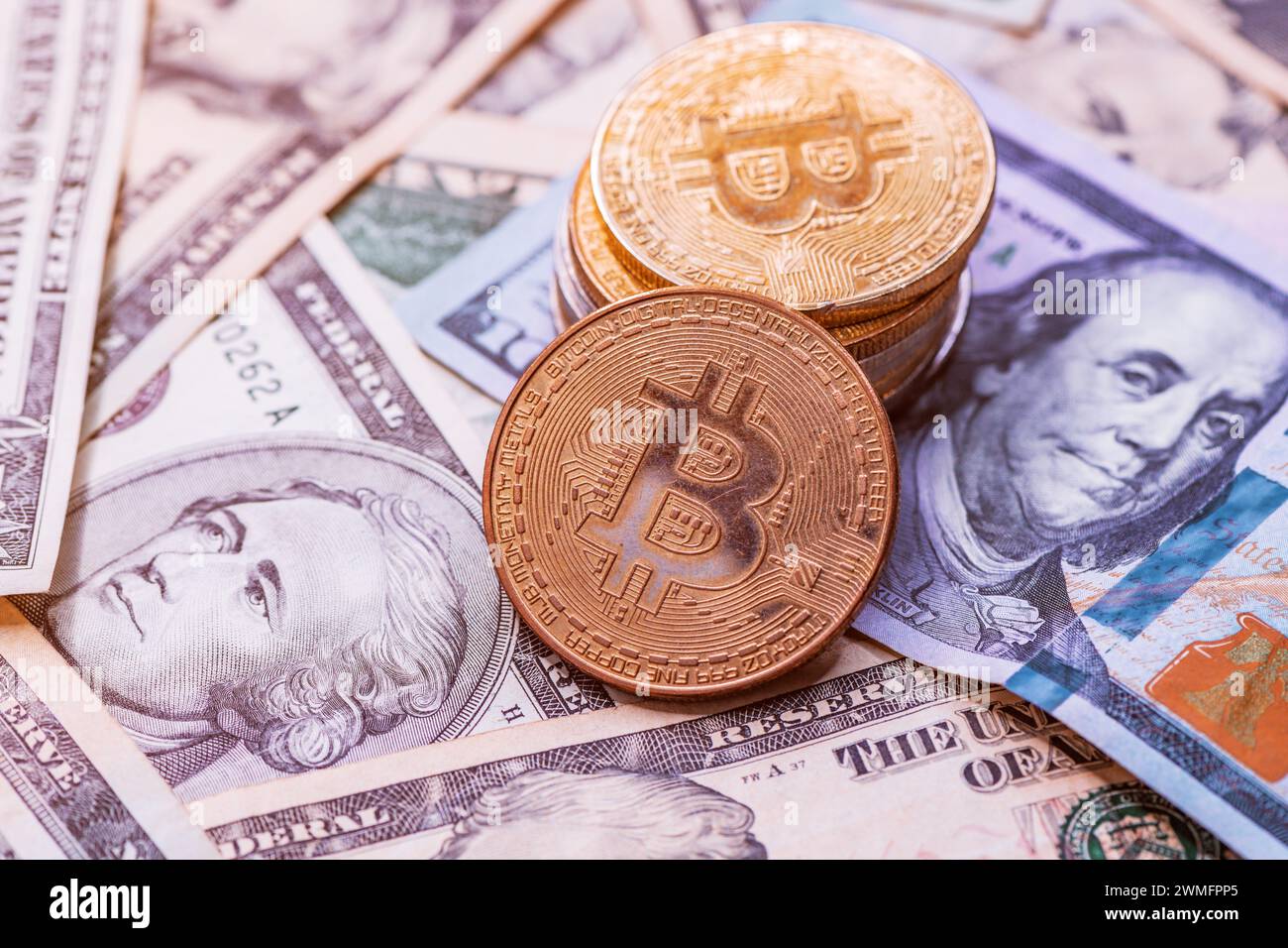 Stack of Bitcoin coins over US dollar banknotes, selective focus Stock Photo