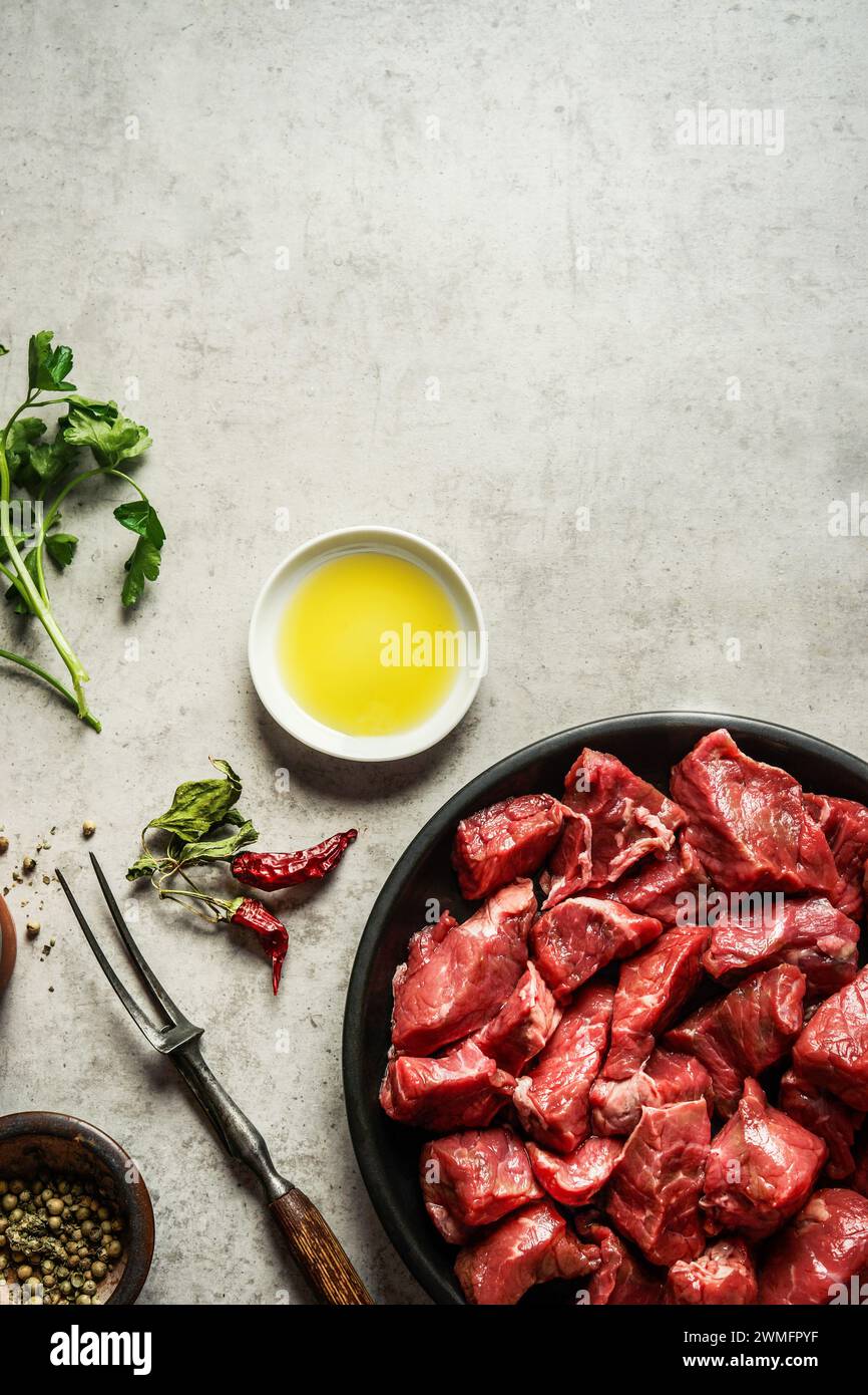 Raw goulash meat on table with cooking ingredients, top view Stock Photo