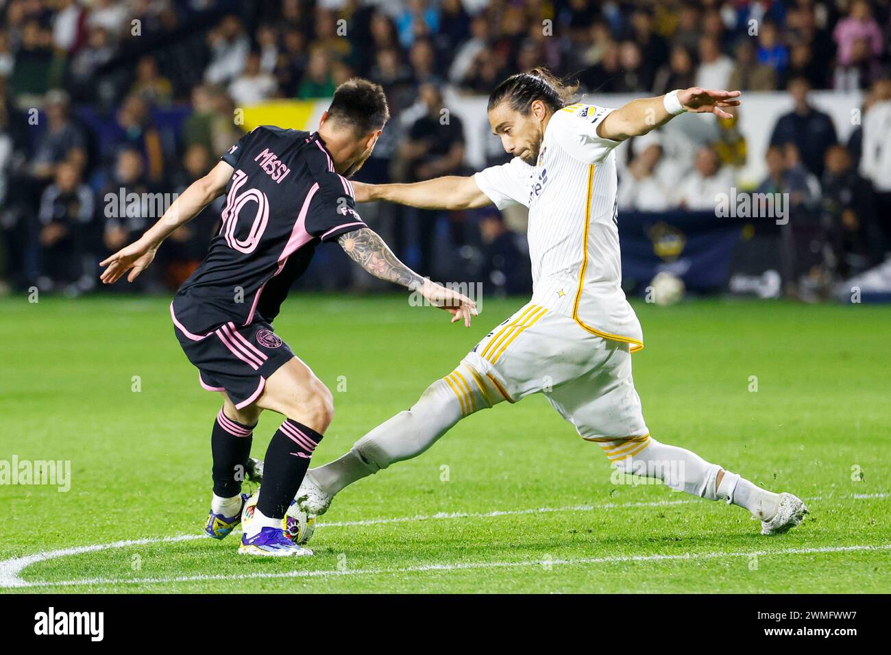 Los Angeles, United States. 25th Feb, 2024. Inter Miami's Lionel Messi (L) and LA Galaxy's Martín Cáceres (R) vie for the ball during an MLS soccer match at Dignity Health Sports Park in Carson. Final Score: LA Galaxy 1:1 Inter Miami Credit: SOPA Images Limited/Alamy Live News Stock Photo