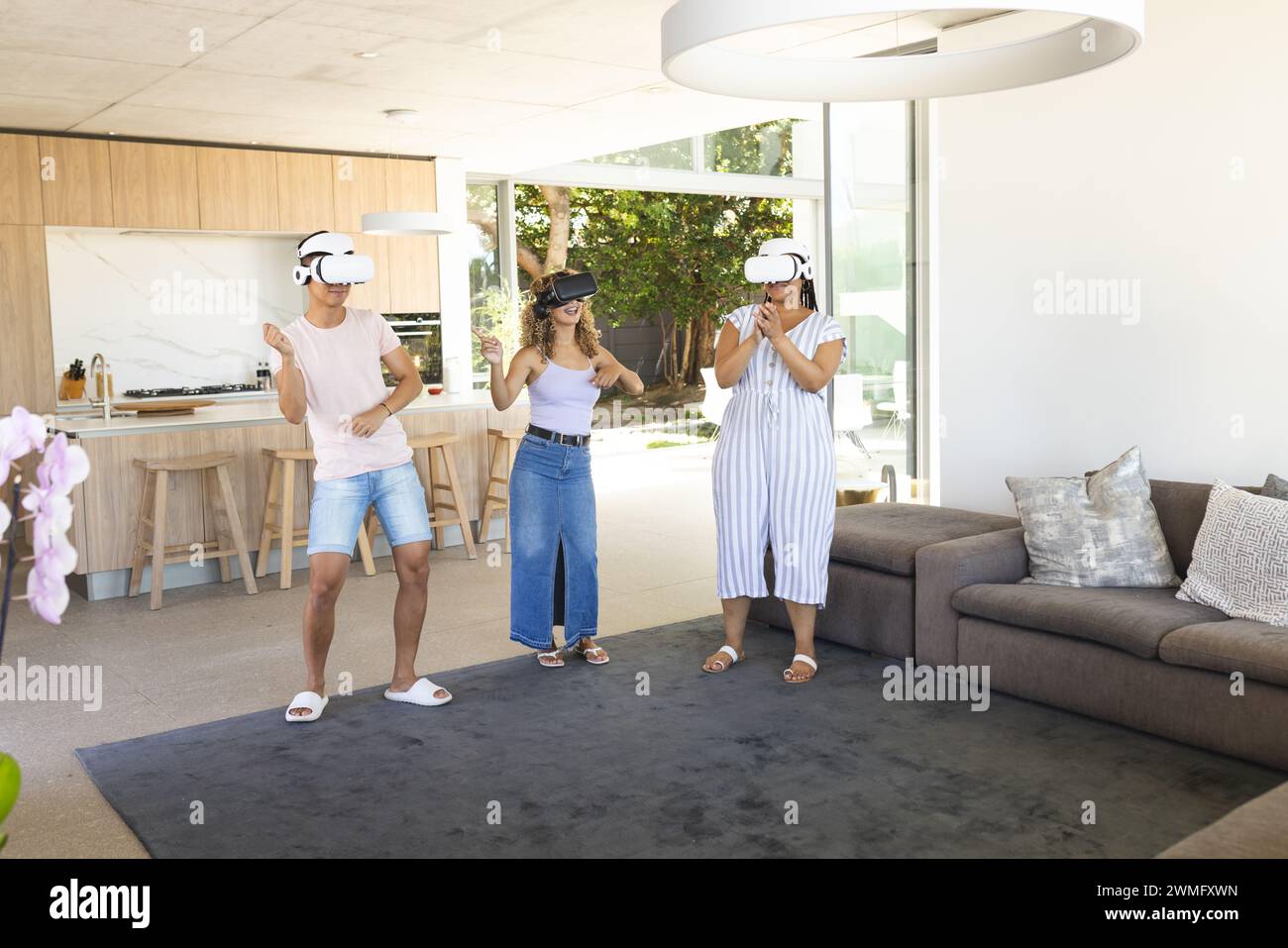 Young Asian man and two young biracial women enjoy virtual reality at home Stock Photo