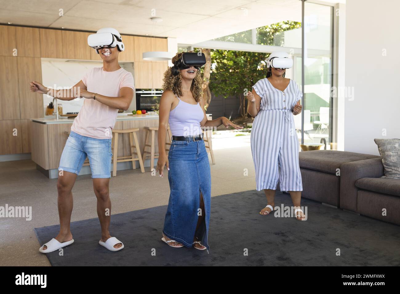 Young Asian man and two young biracial women enjoy virtual reality at home Stock Photo