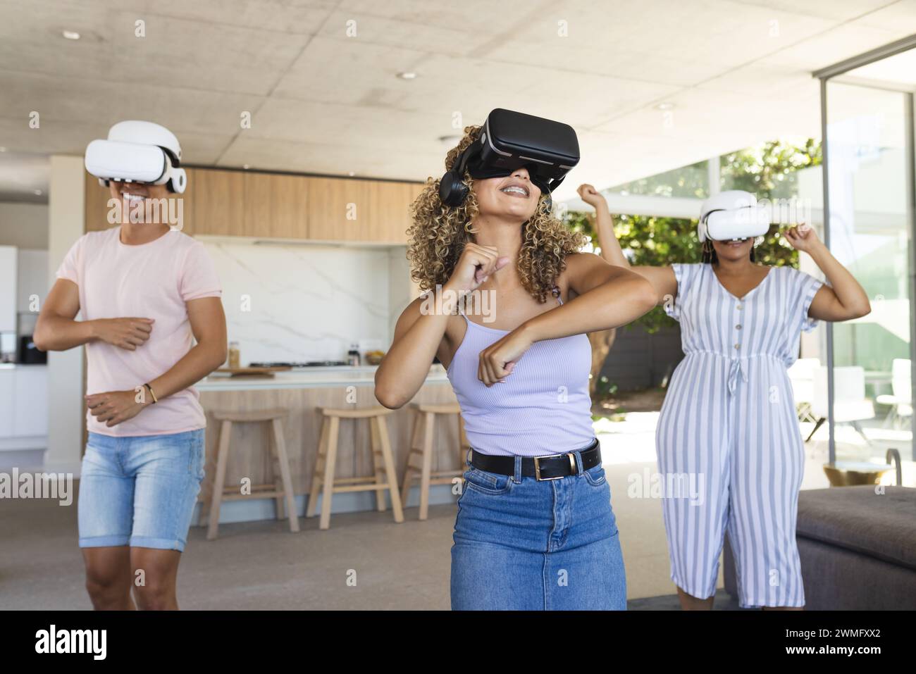 Diverse friends enjoy virtual reality games at home Stock Photo