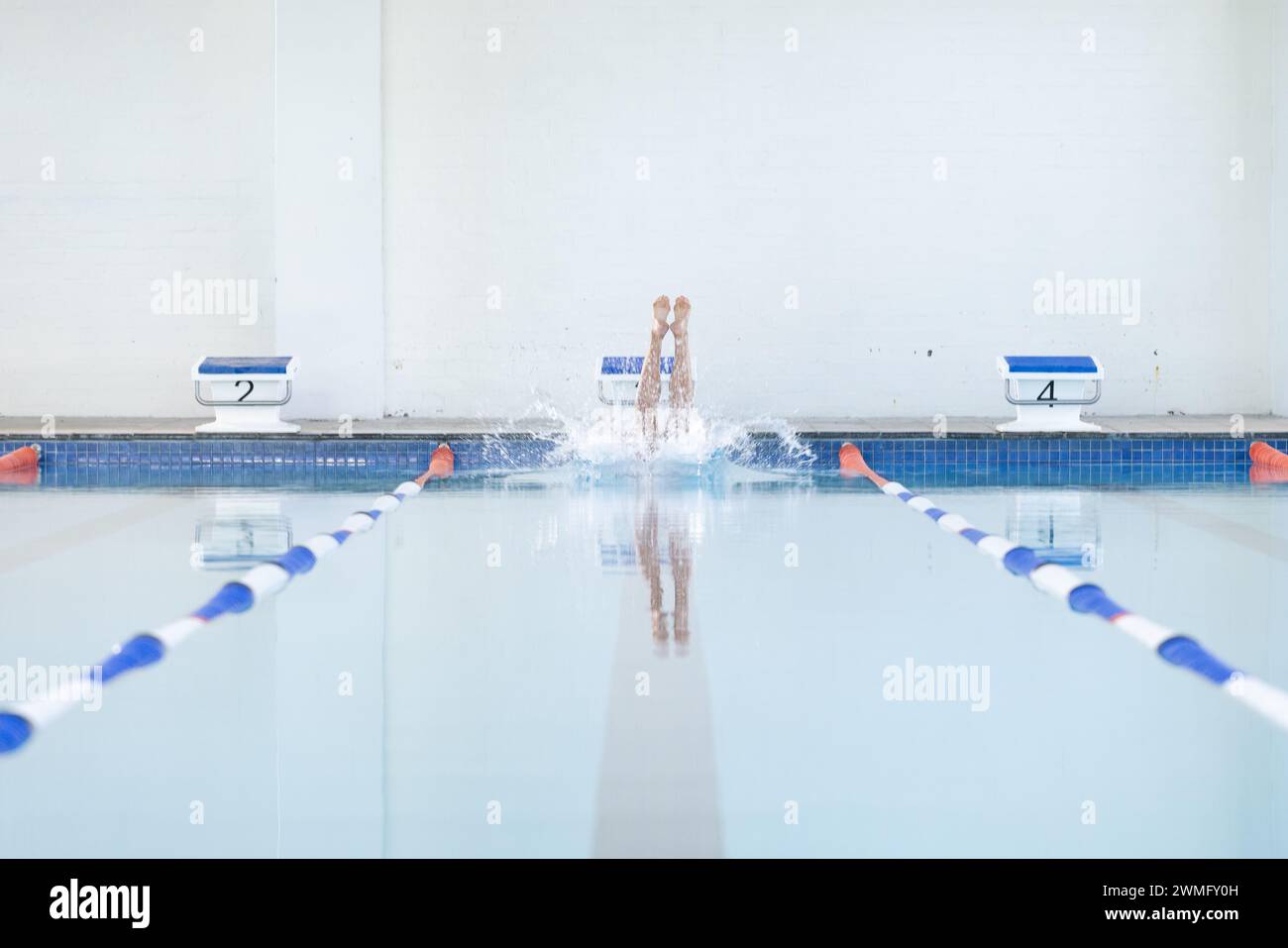 A swimmer dives into a pool at a competitive swimming event Stock Photo