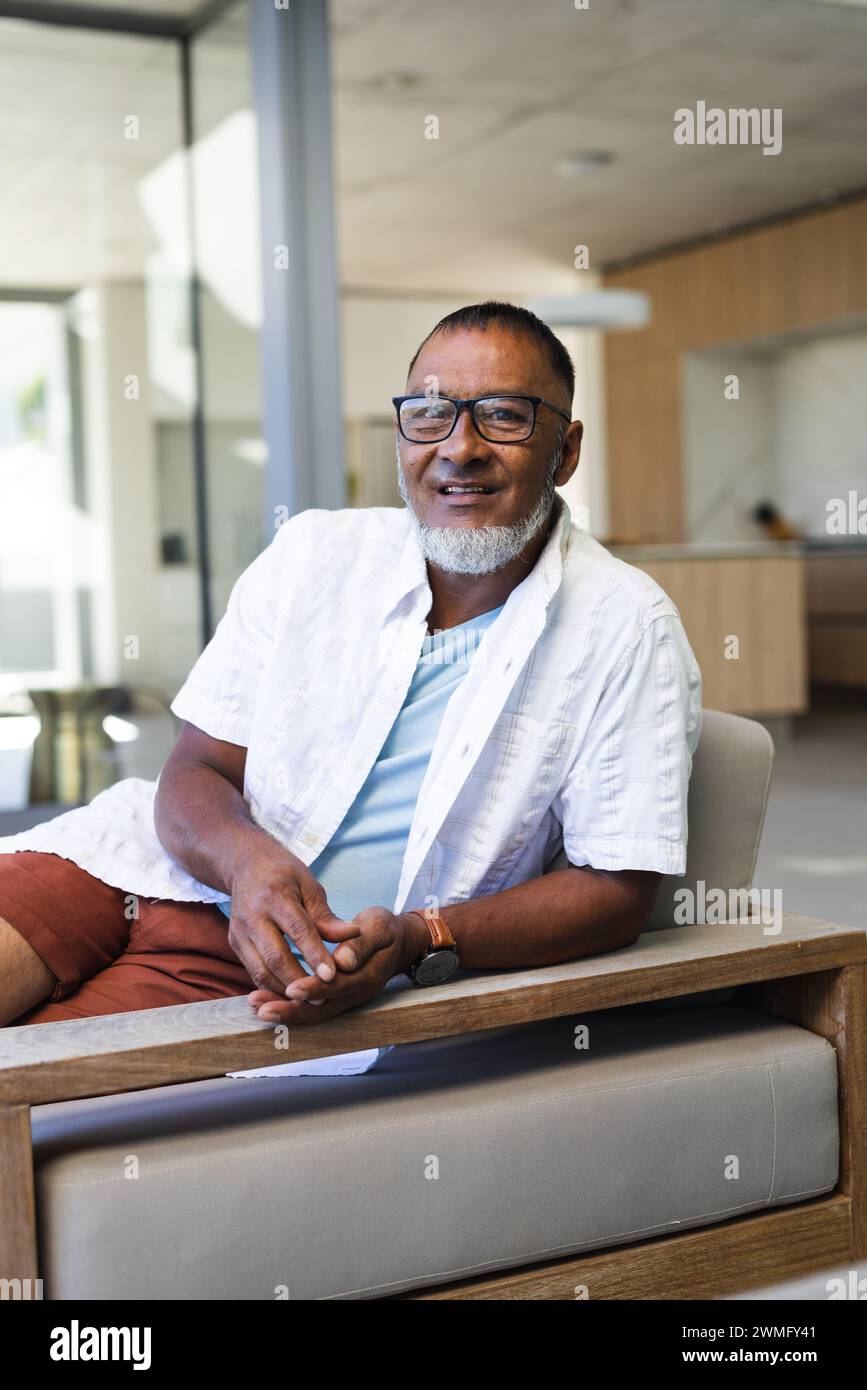 A senior smiling biracial man sits comfortably at home Stock Photo