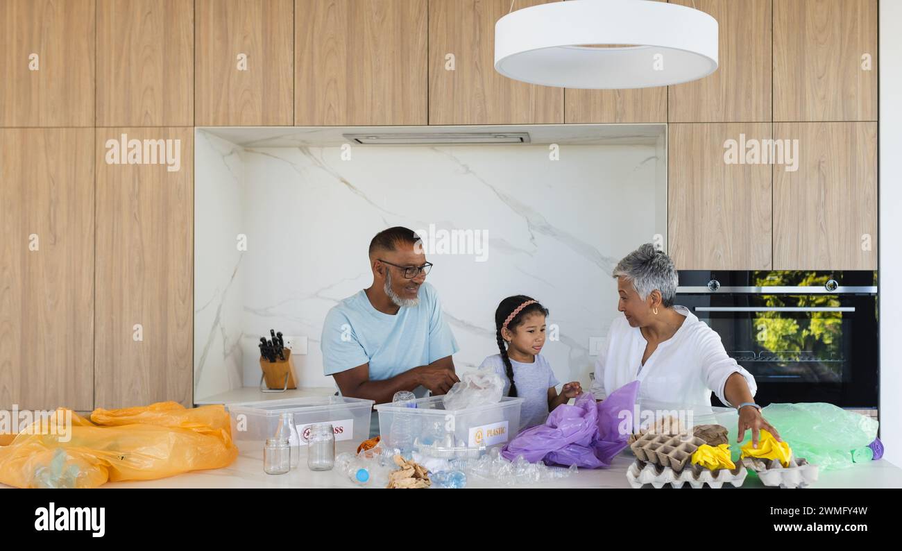 Biracial grandparents and granddaughter sort recyclables in a modern kitchen Stock Photo