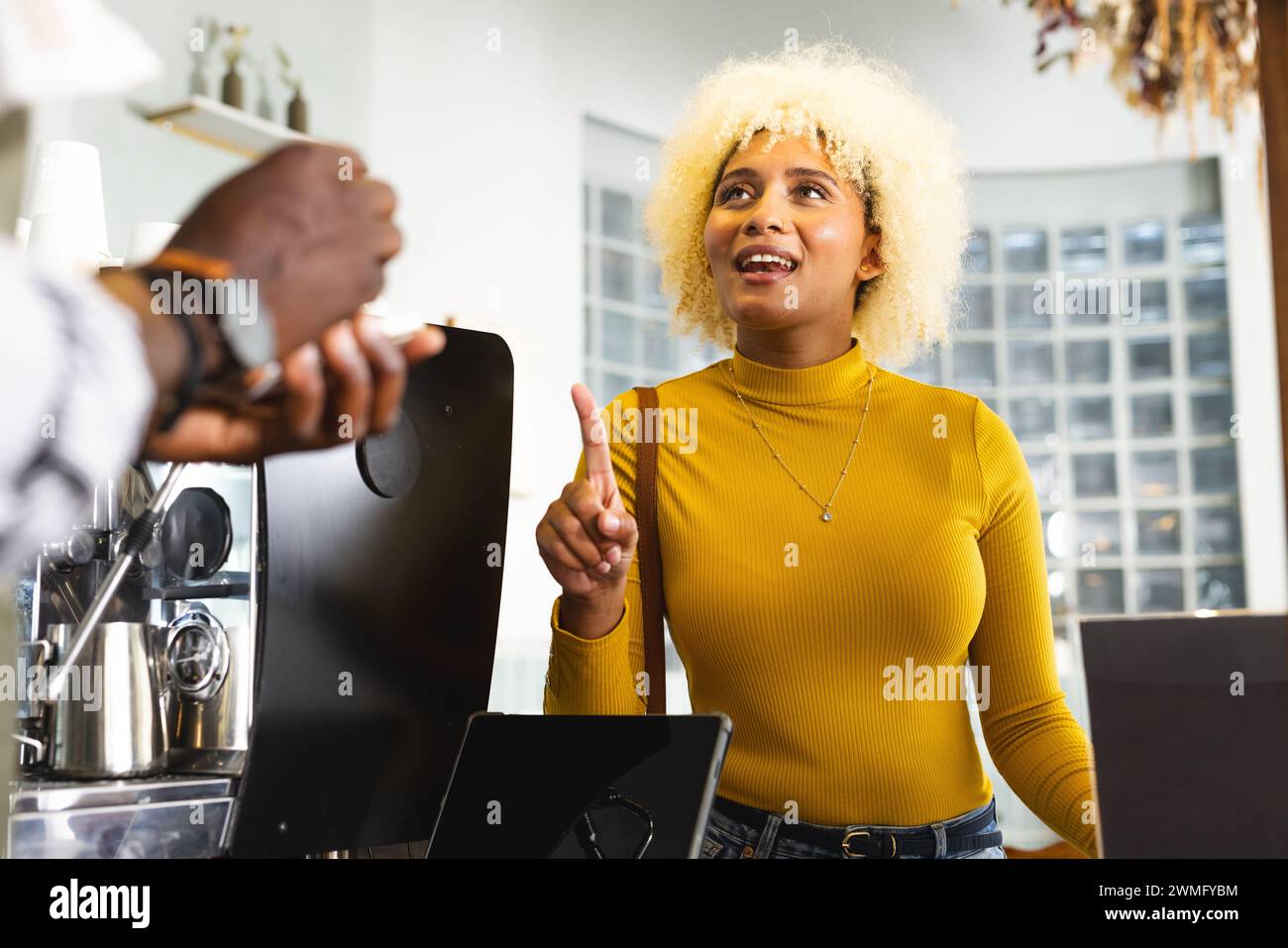 Young African American male barista and biracial woman in a lively discussion at a coffee shop Stock Photo