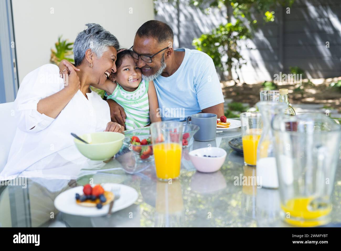 Biracial couple enjoys breakfast outdoors with their granddaughter Stock Photo