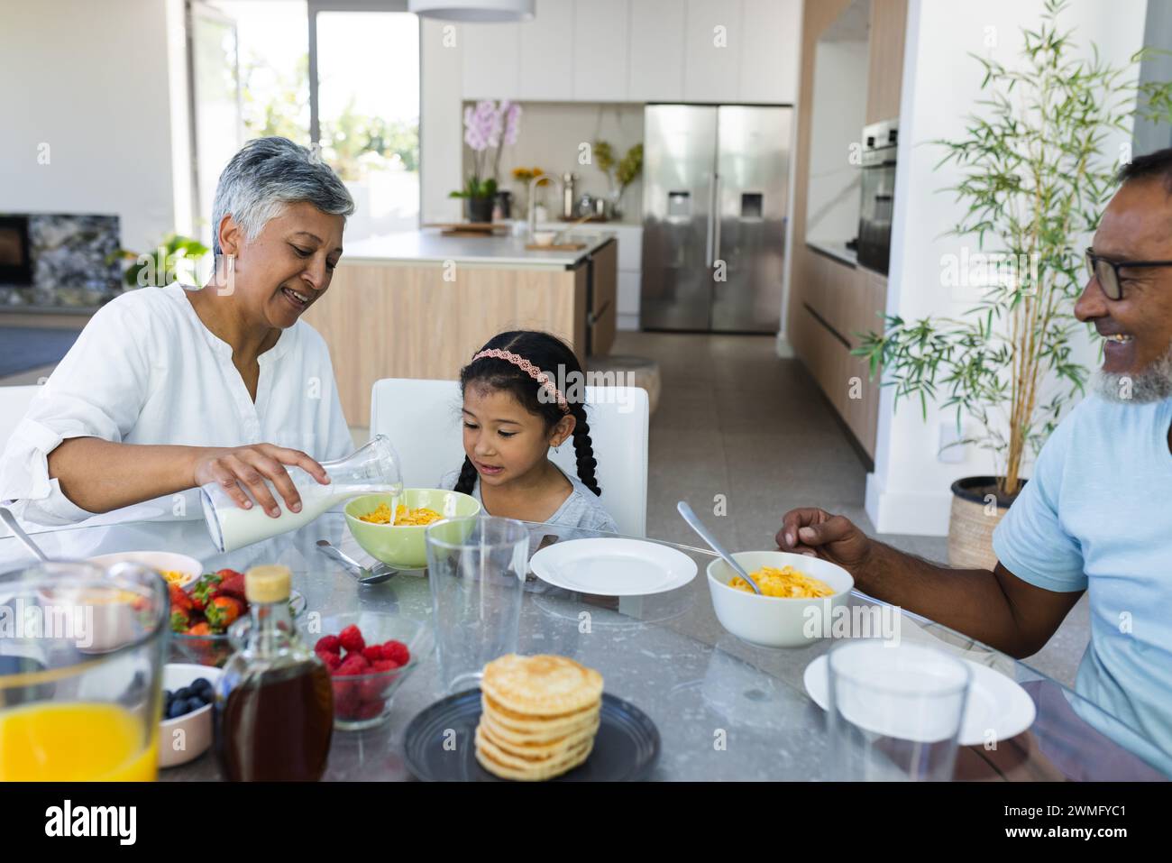 Biracial grandparents enjoy breakfast together at home Stock Photo