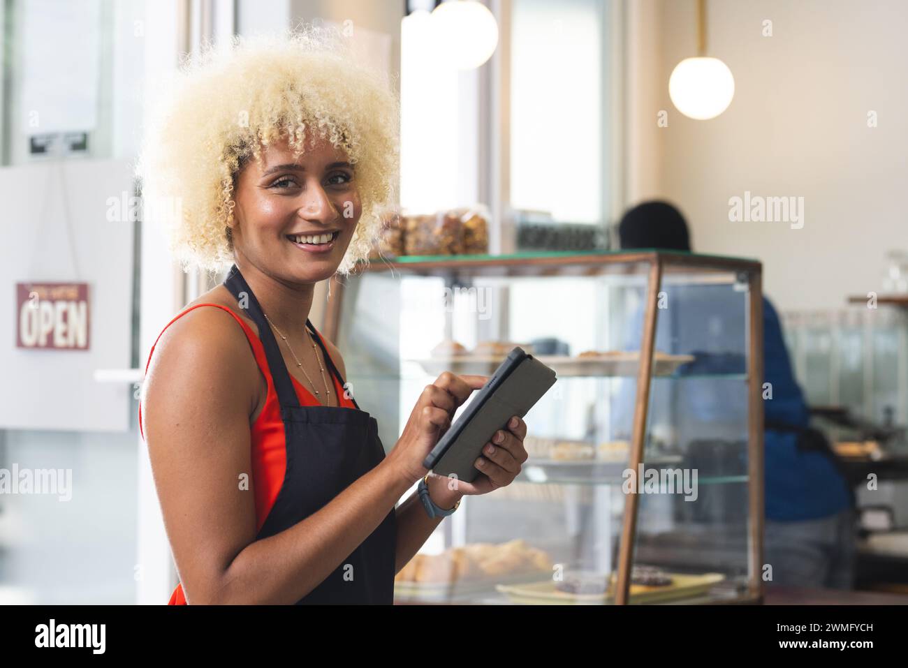 A smiling biracial woman operates a point of sale system in a cafe, with copy space Stock Photo