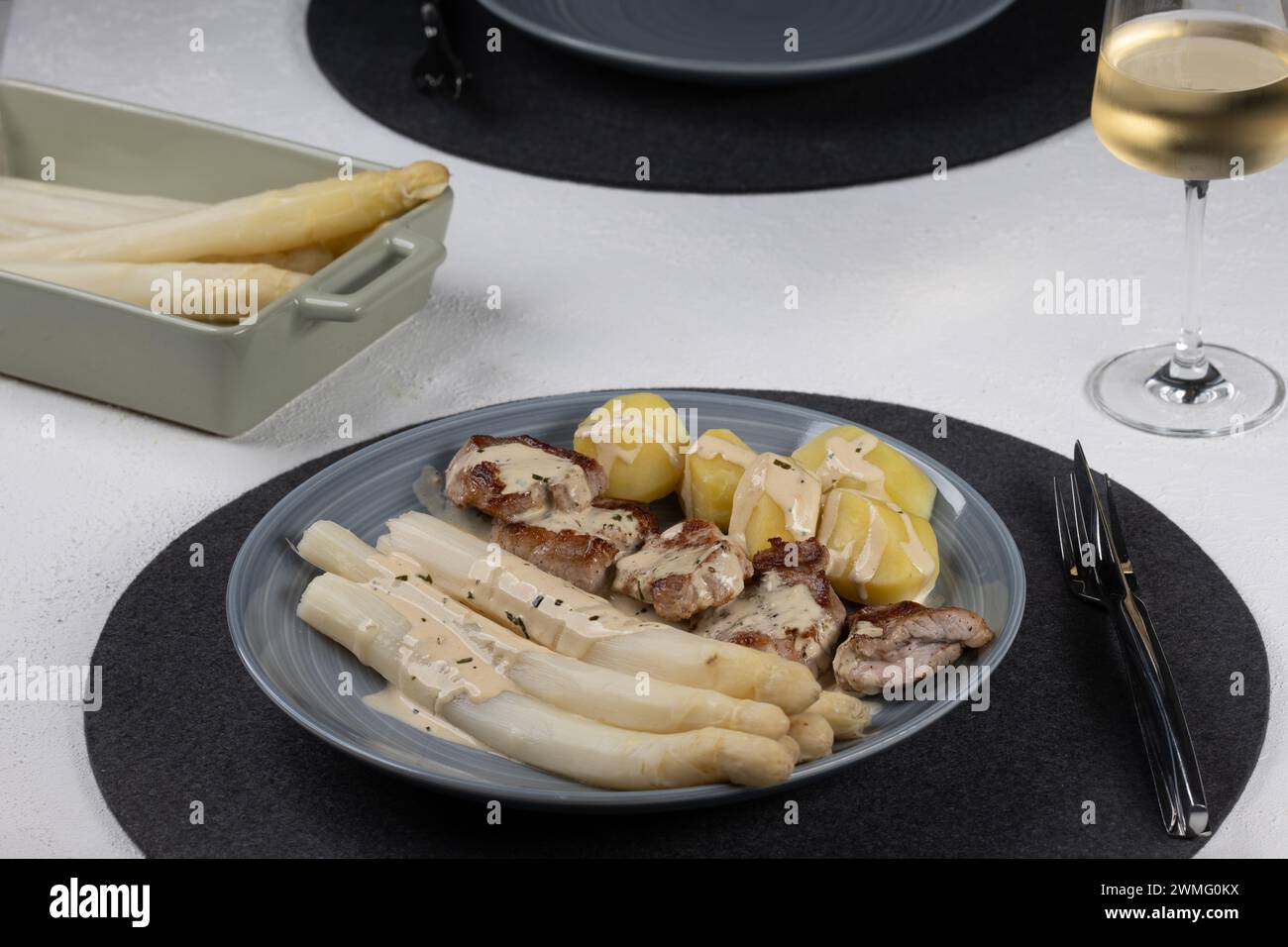 Pork tenderloin with asparagus and mustard - tarragon sauce, white asparagus, potatoes, white wine Stock Photo