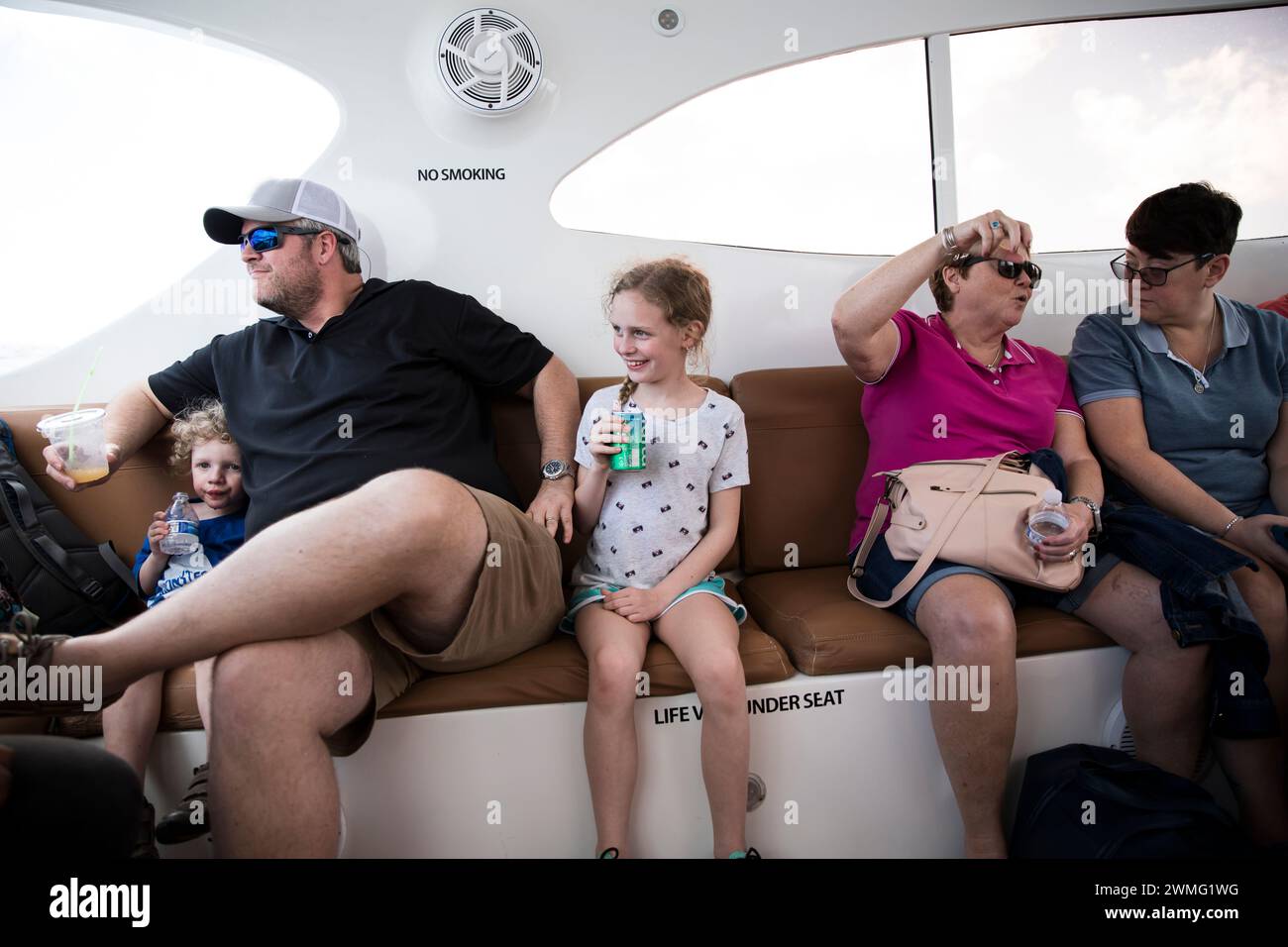 Large Family Sits Together on Open Air Caribbean Ferry Stock Photo