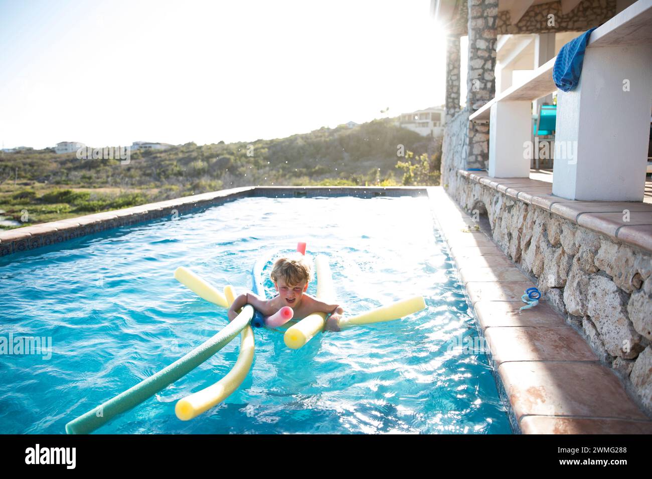 Young Boy Swims With Noodles in Infinity Pool on Caribbean Vacation Stock Photo