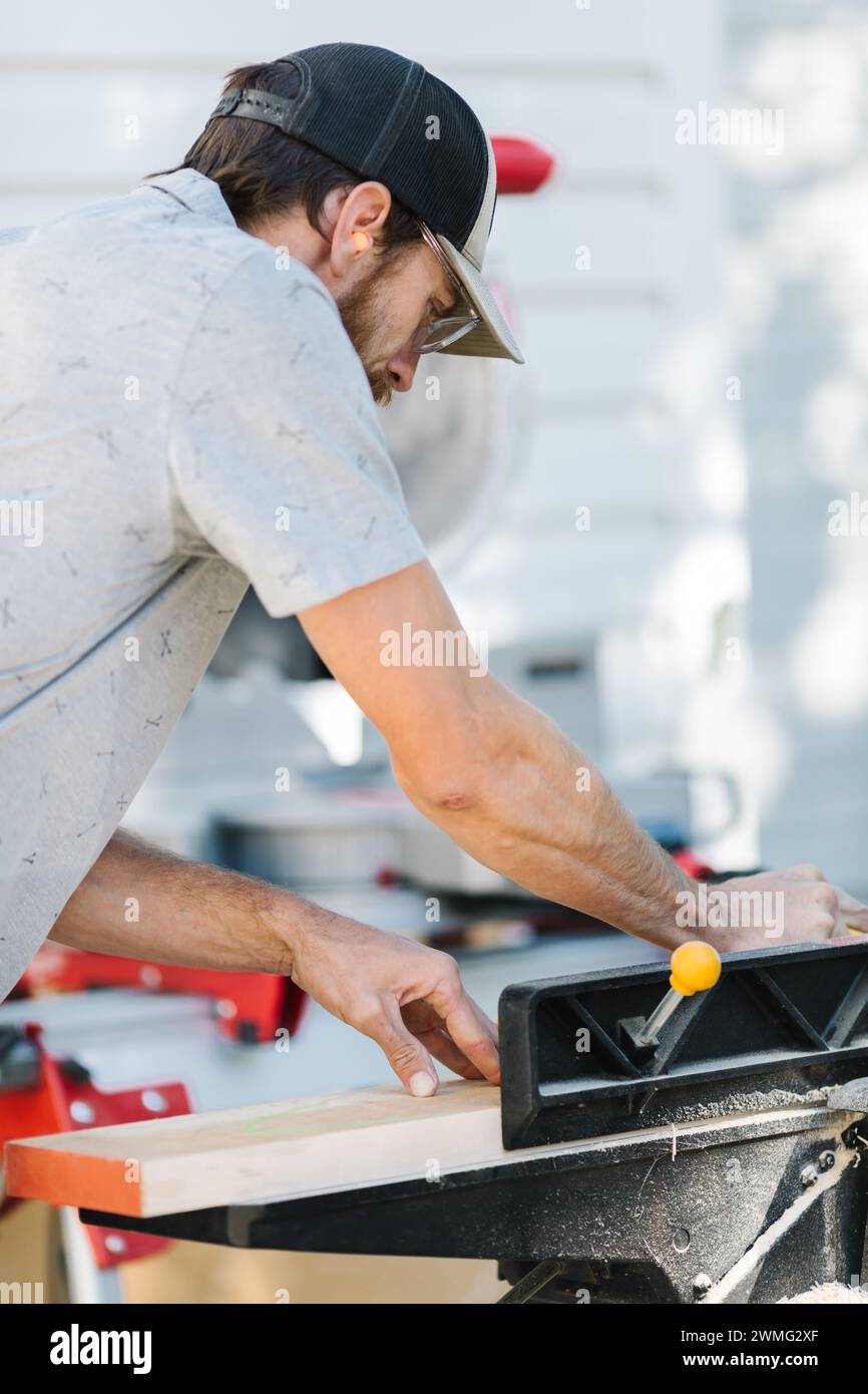 Intently focused carpenter sawing wood. Stock Photo