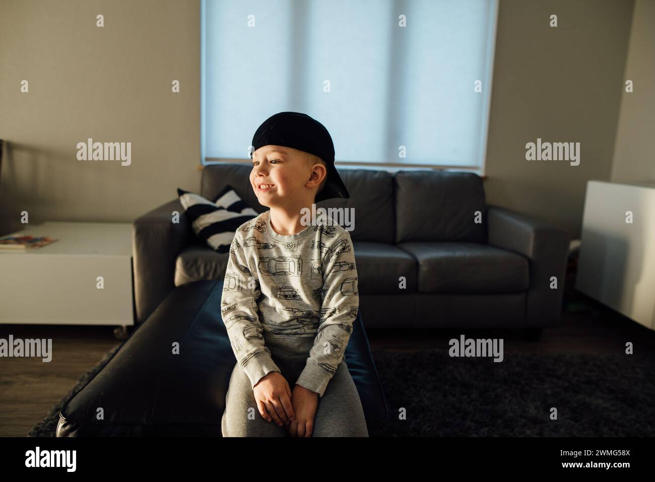 Profile of young boy wearing backwards baseball cap and smiling Stock Photo