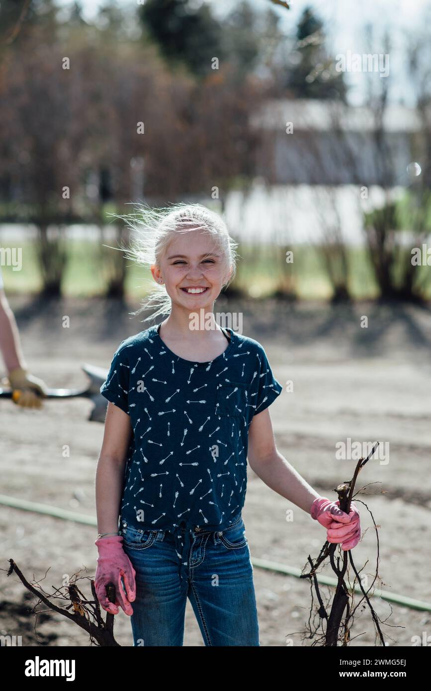 Close up of preteen girl doing yardwork chores while smiling Stock Photo