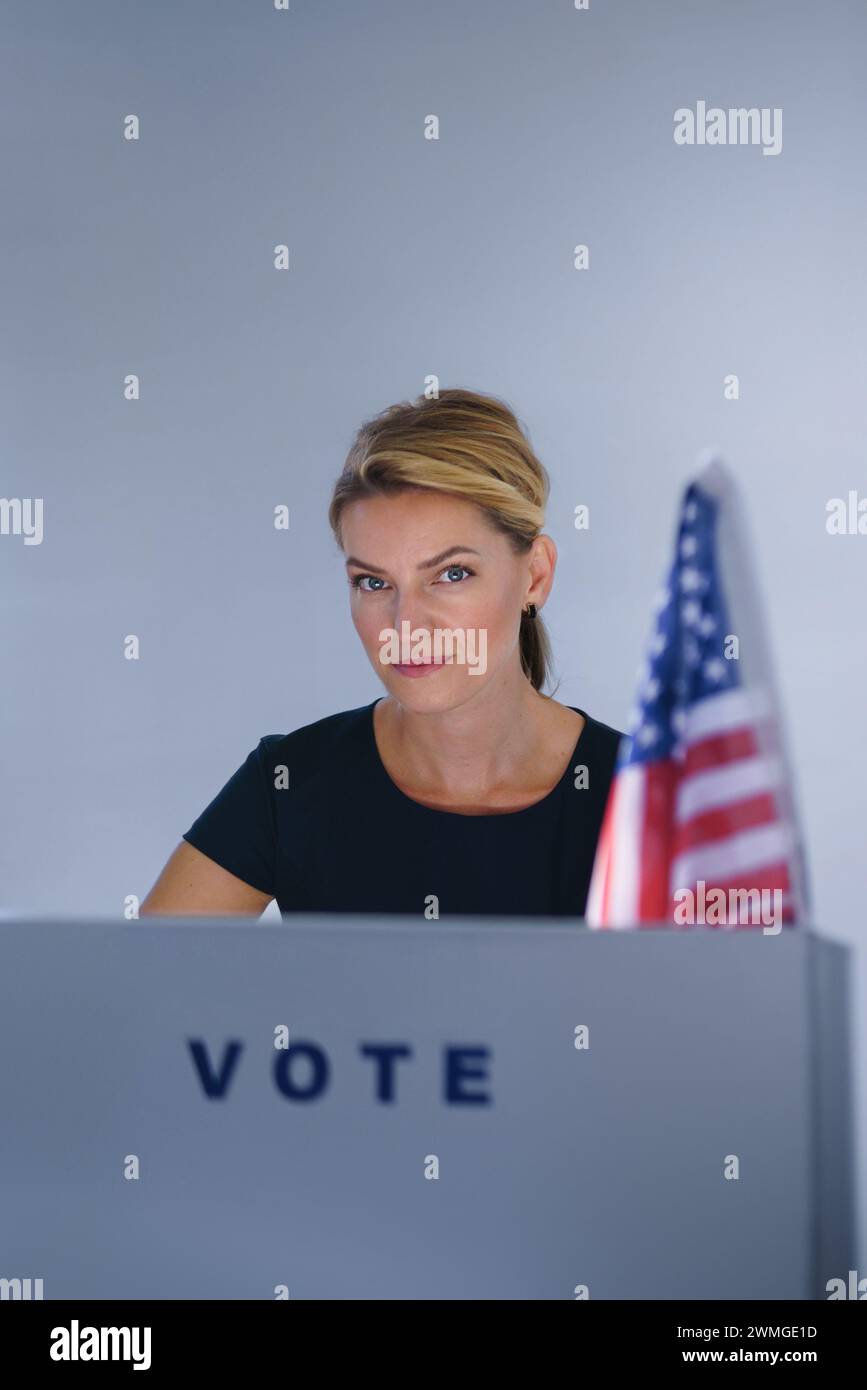 Portrait of female voter filling election ballot paper. US citizen voting in polling place on election day, usa elections. Stock Photo