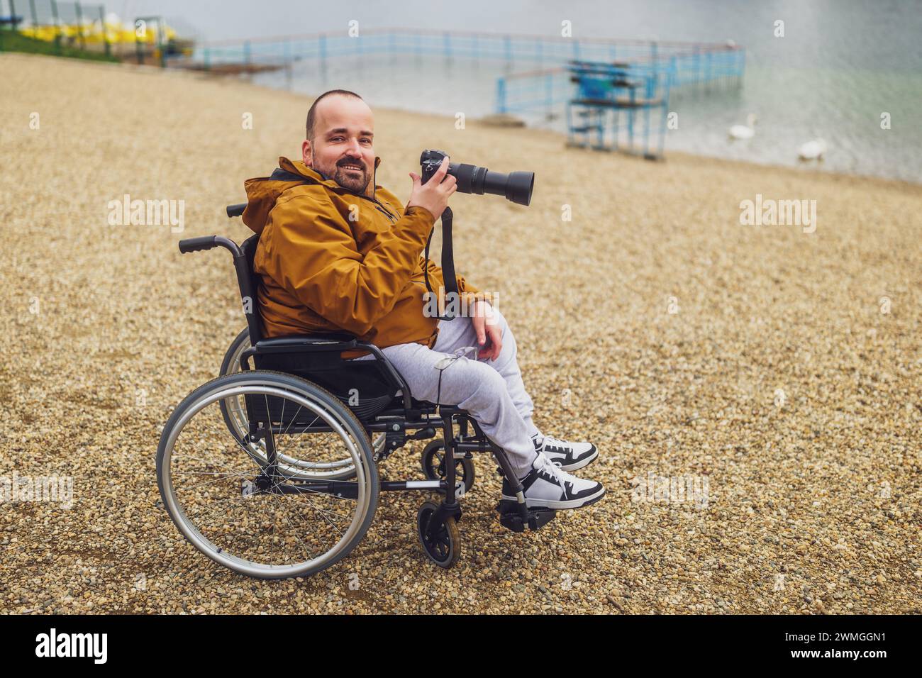 Paraplegic handicapped man in wheelchair is photographing outdoor. Stock Photo