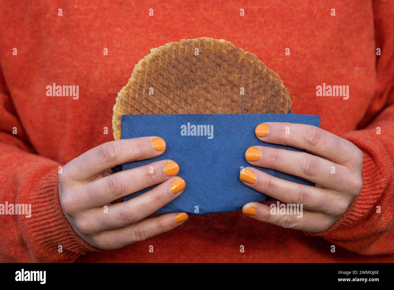 Woman holds traditional dutch Stroopwafel, a round waffle cookie treat popular in The Netherlands Stock Photo