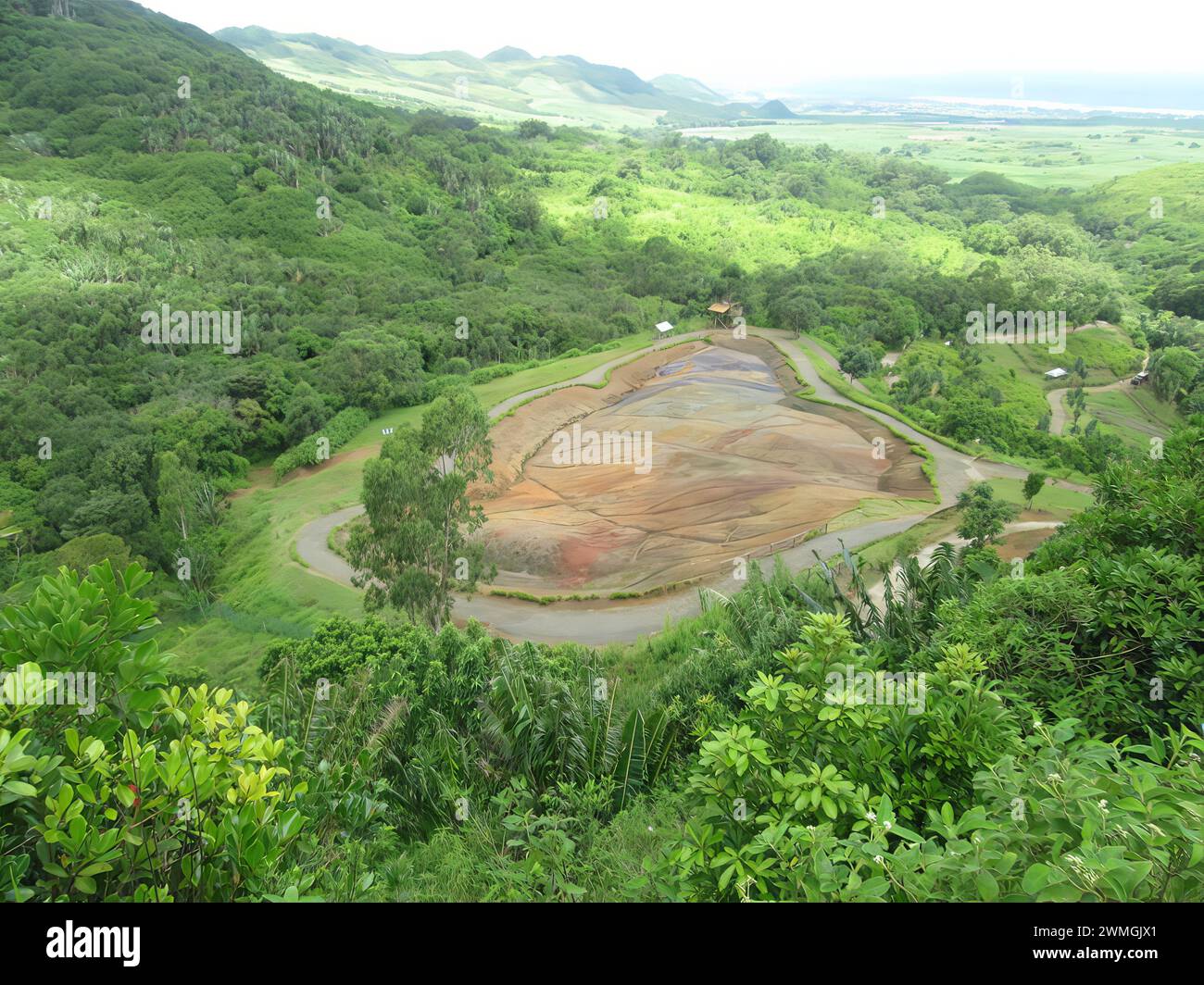 A vast mining site, water, and lush valley with distant mountains Stock Photo
