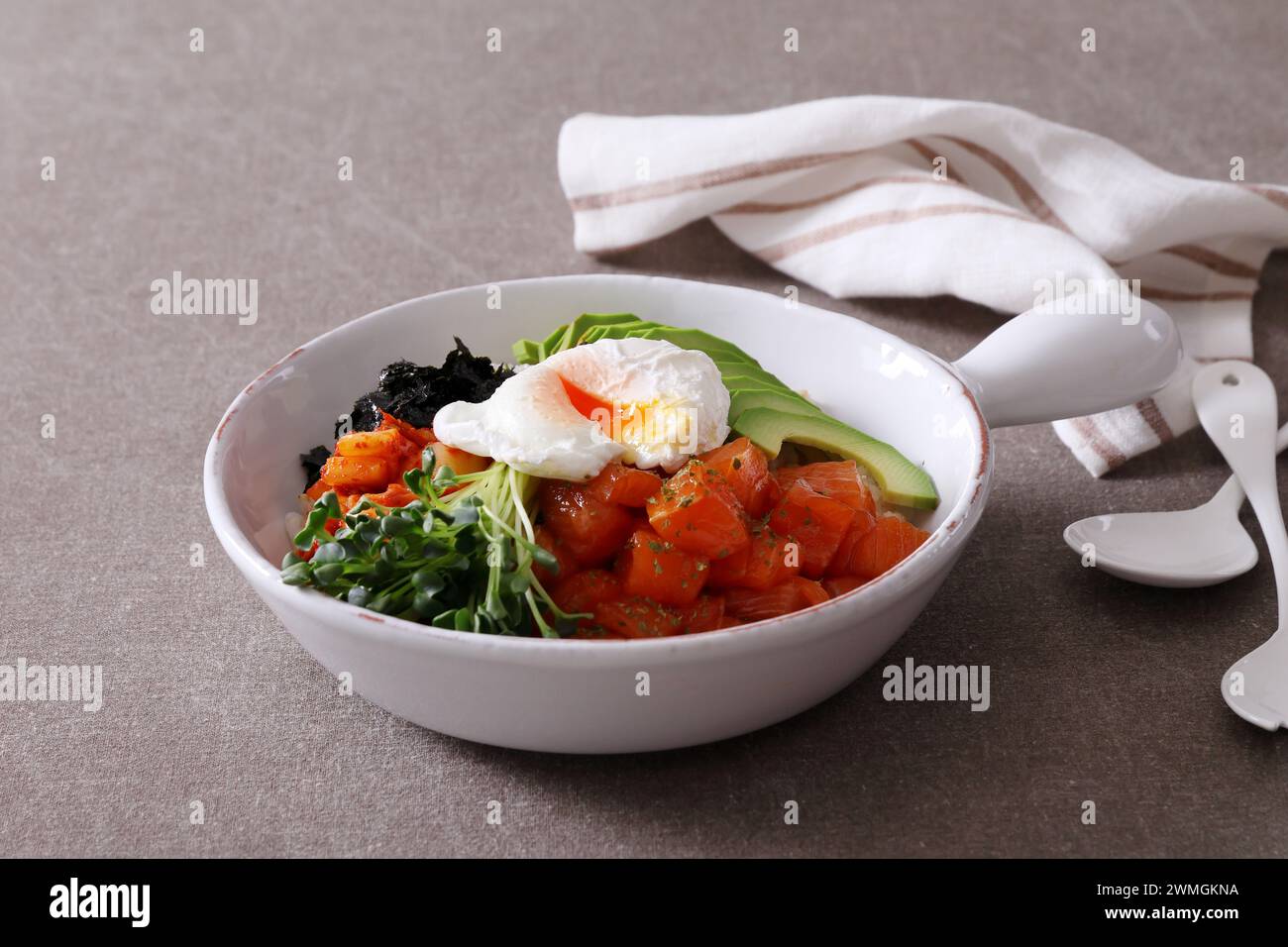 Korean food. Salmon poke bowl with avocado, arugula and poached egg ...