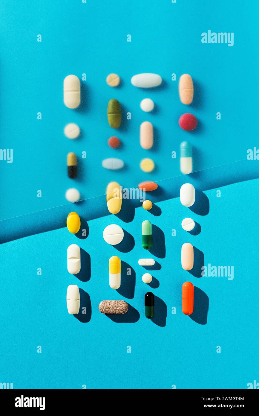 Colorful pills on blue background, medical background. Directly above shot. Stock Photo