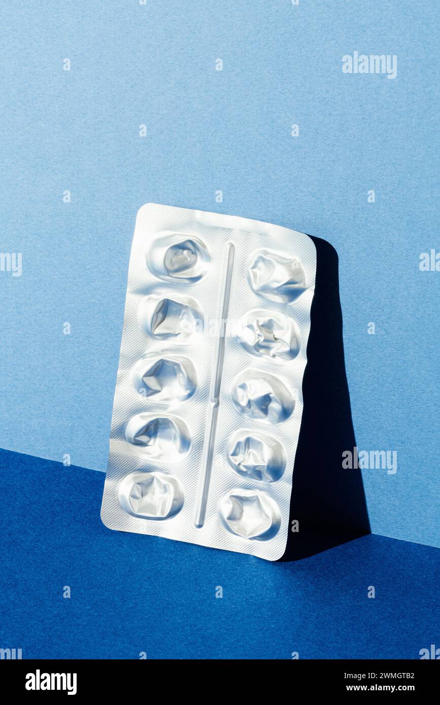 Empty medicine blister pack leaning on blue background. Isolated studio shot. Stock Photo