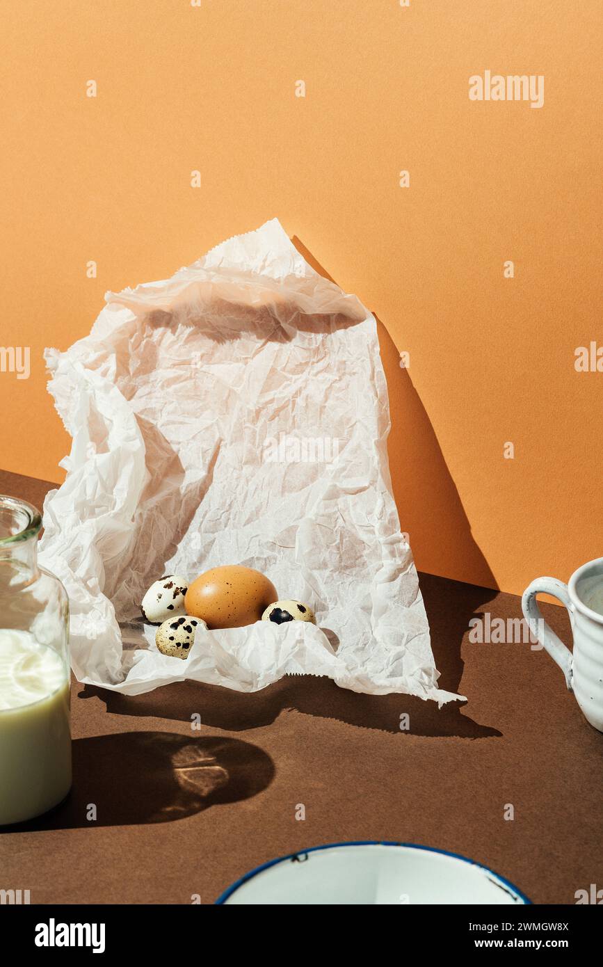 Eggs in a white paper with milk in glass bottle on brown background. Sun light effect, high angle shot. Stock Photo