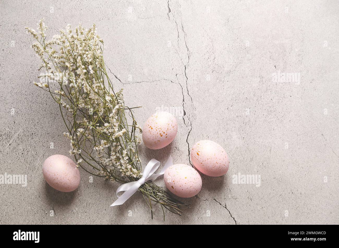 Pink Easter eggs with golden spots  and gypsophila flowers on gray stone background with copy space. Stock Photo