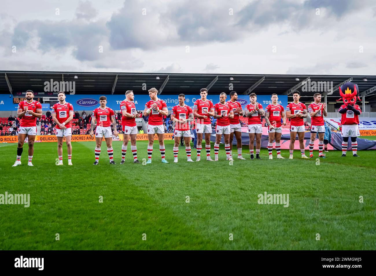 Salford team line up for a moment applause for Malkum Alker before the game. Salford Red Devils Vs Castleford Tigers, Salford Community Stadium, 25th February 2024. Credit: James Giblin/Alamy Live News Stock Photo