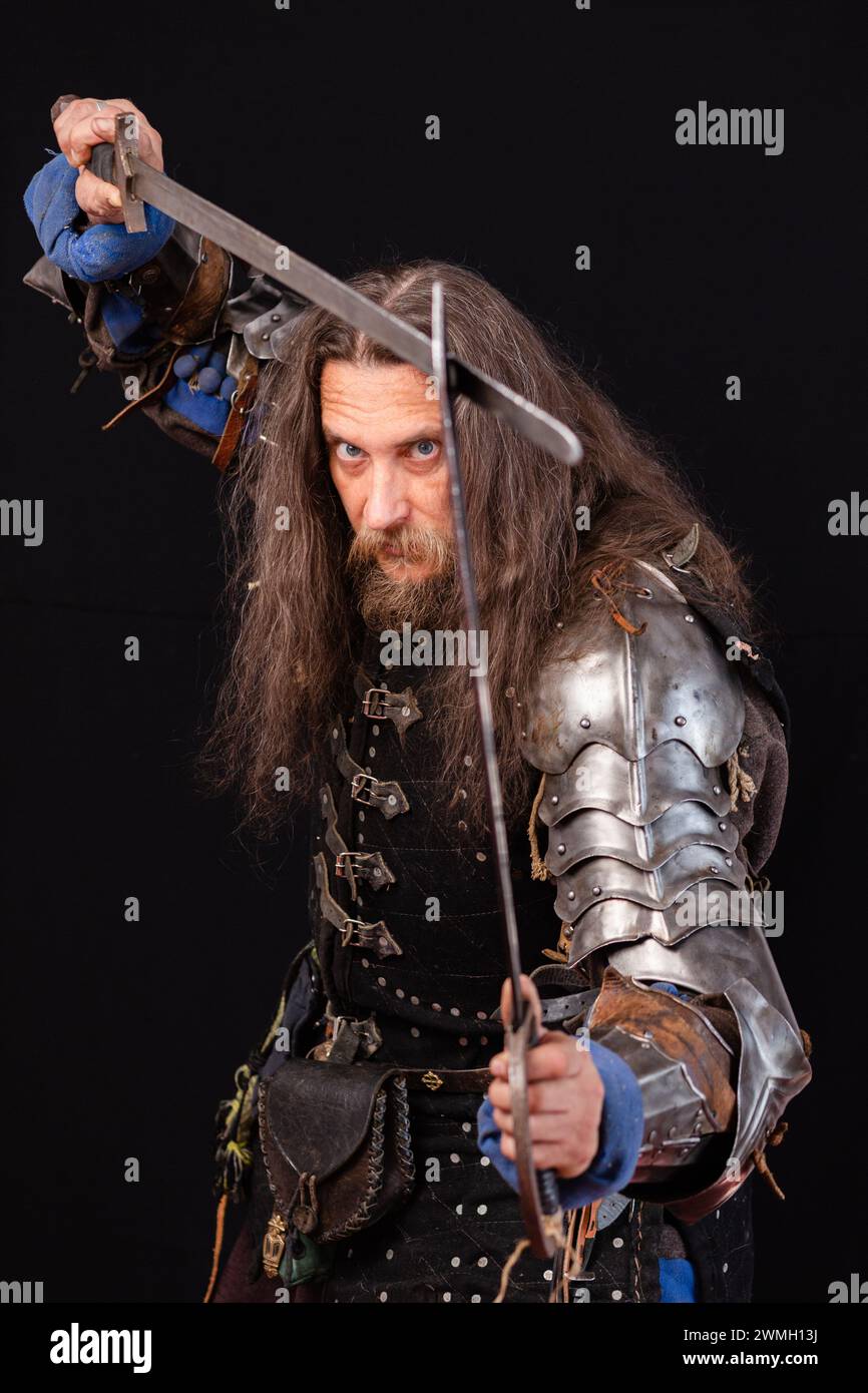 Vertical composition. Portrait of a medieval knight with a characteristic historical appearance with with two swords. ESports. Stock Photo