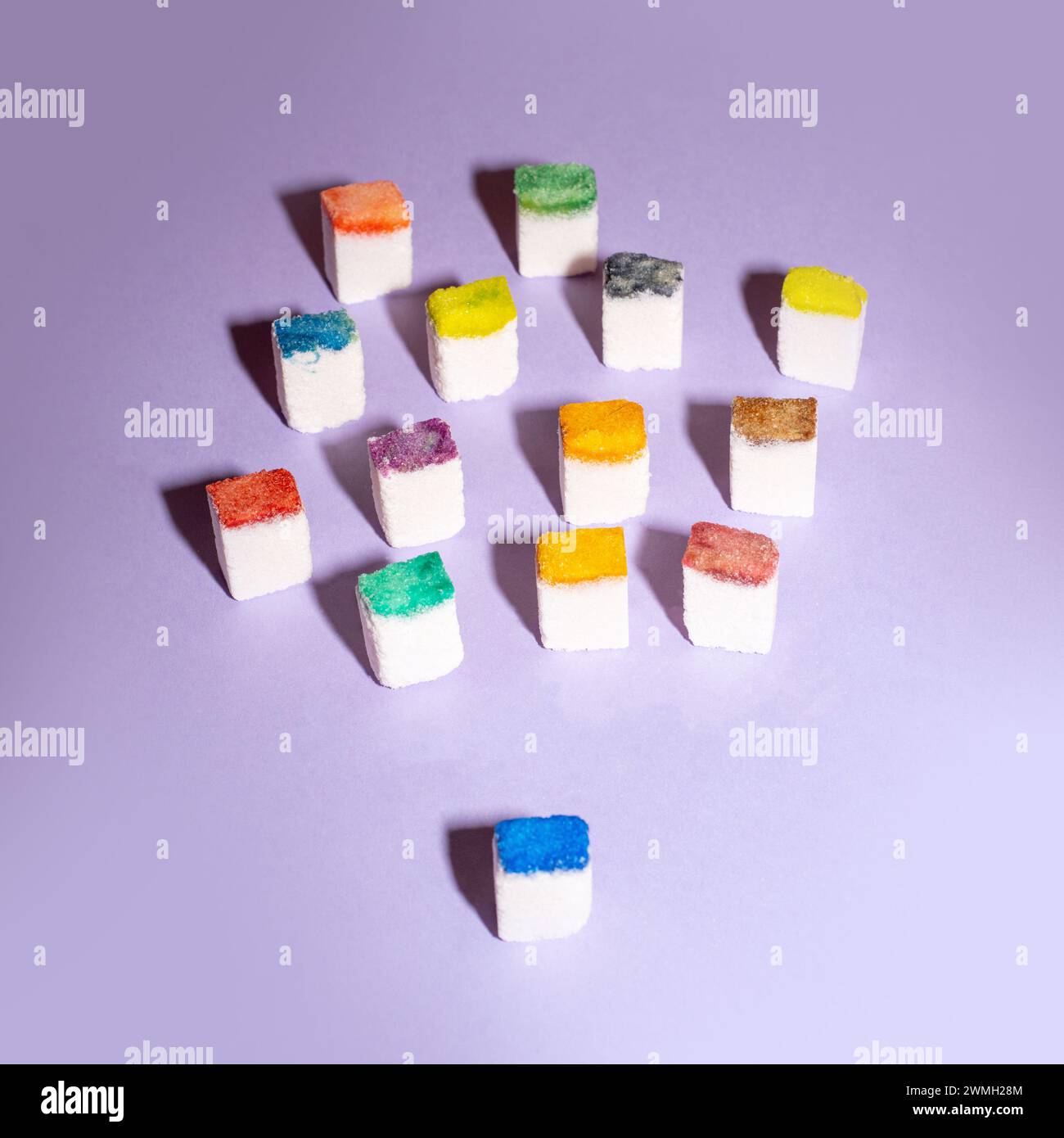 Colorful sugar cubes form a crowd on a purple background. People metaphor. Creative food concept. Stock Photo