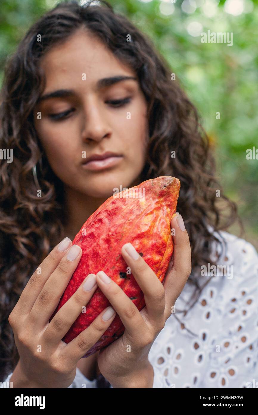 Young girl holds cocoa fruit at plantation in Henri Pittier National
