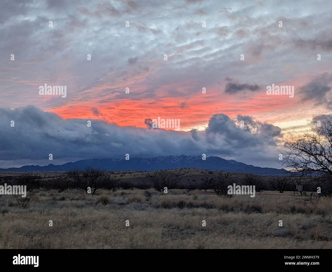 A Sunset over mountain with distant trees and clouds above Stock Photo