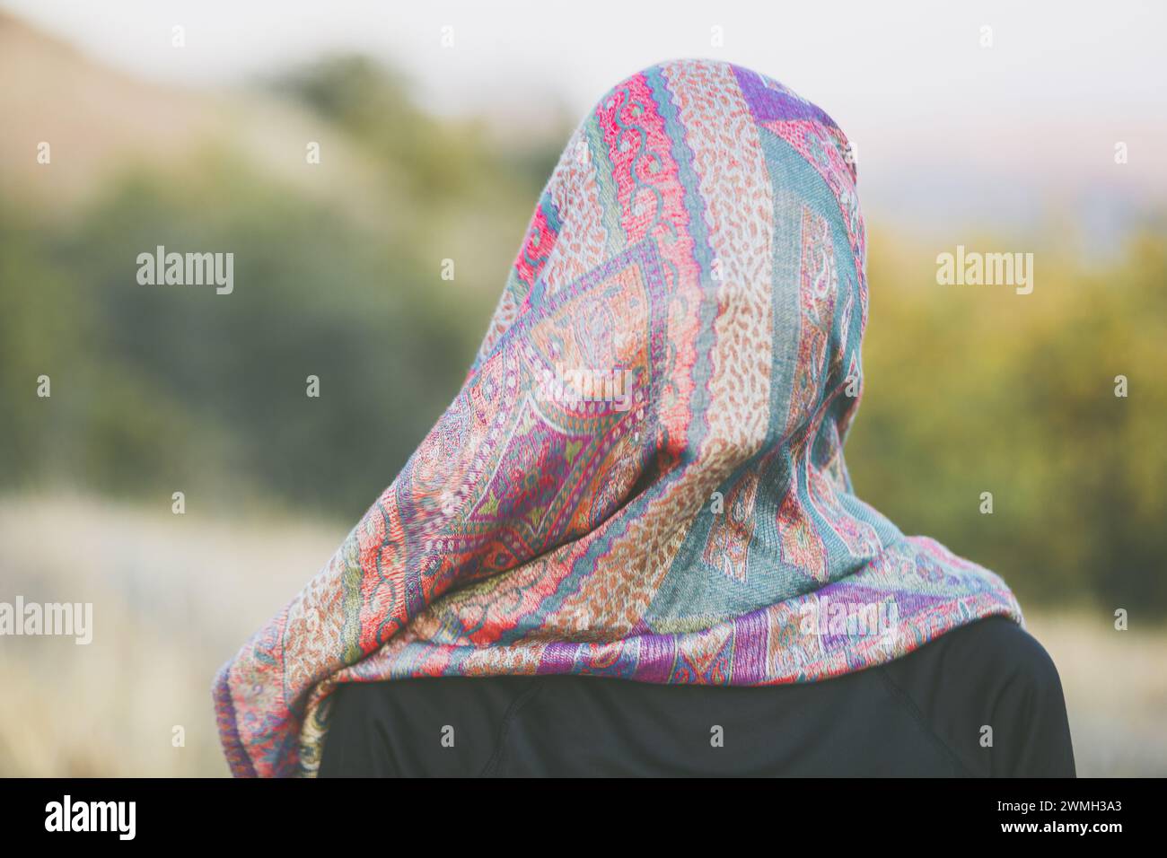 Portrait of an adult woman with a scarf on her head that covers her face in an autumn landscape. Visualization of a psychological problem and analogy Stock Photo