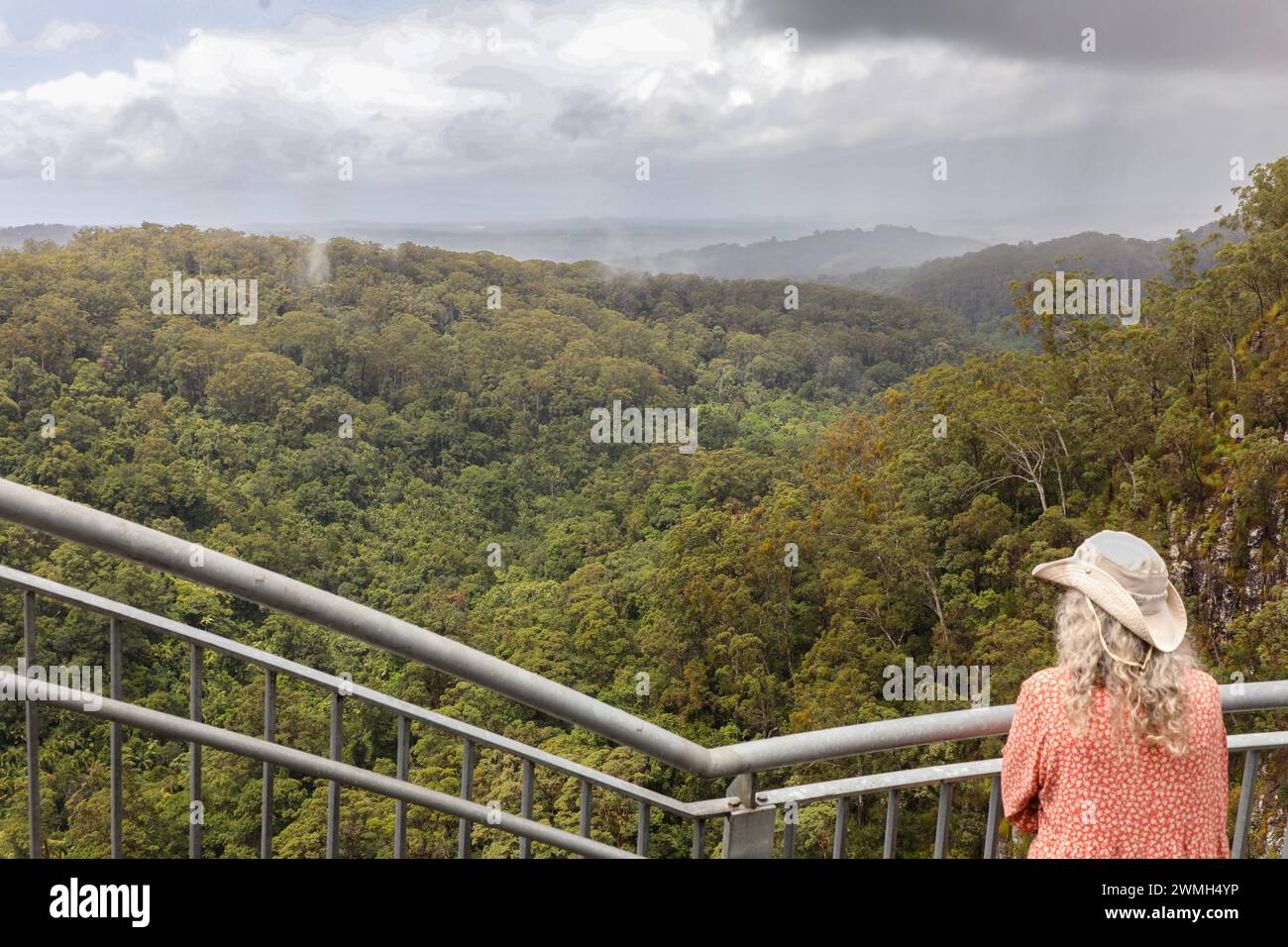 A woman, on a round-the-world adventure tour, stands on the Minyon Falls lookout in Nightcap National Park near Alstonville, NSW, Australia. Stock Photo