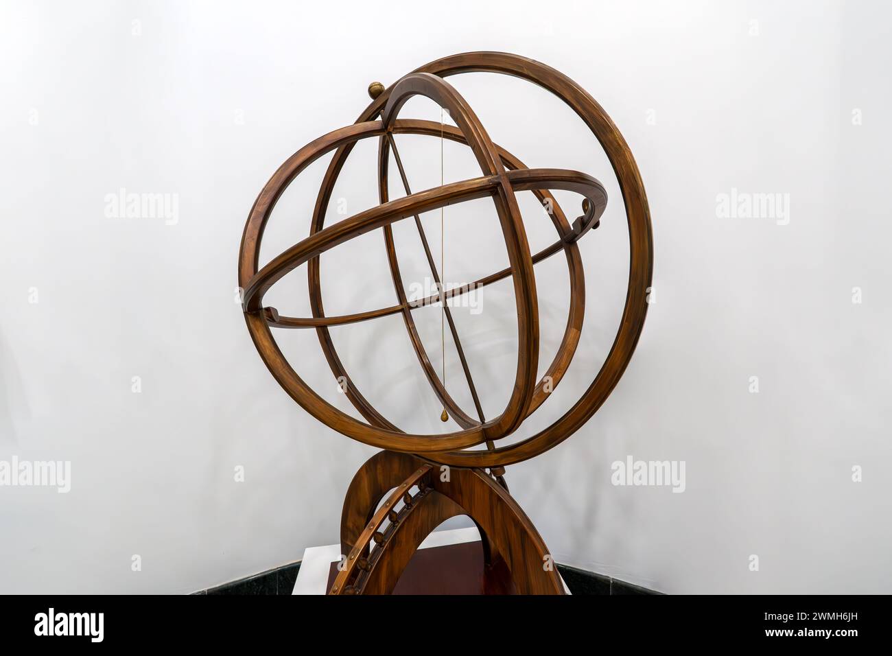 Antique brass armillary sphere on a wooden stand on a white background. the ancient scheme of the movement of celestial stars Stock Photo