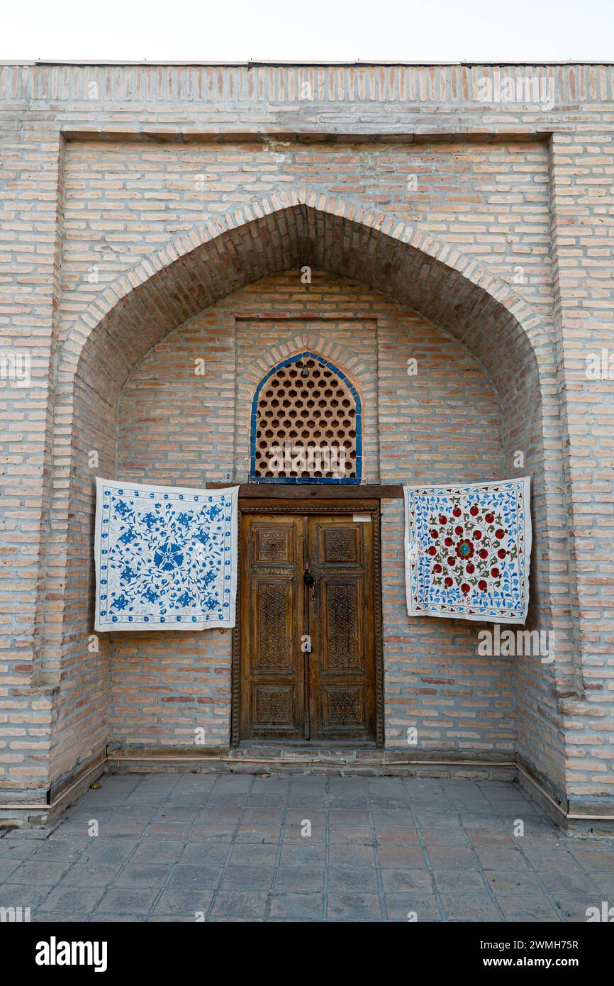 small carpets hang on the wall in front of the entrance to the souvenir shop in Samarkand, Uzbekistan. Stock Photo