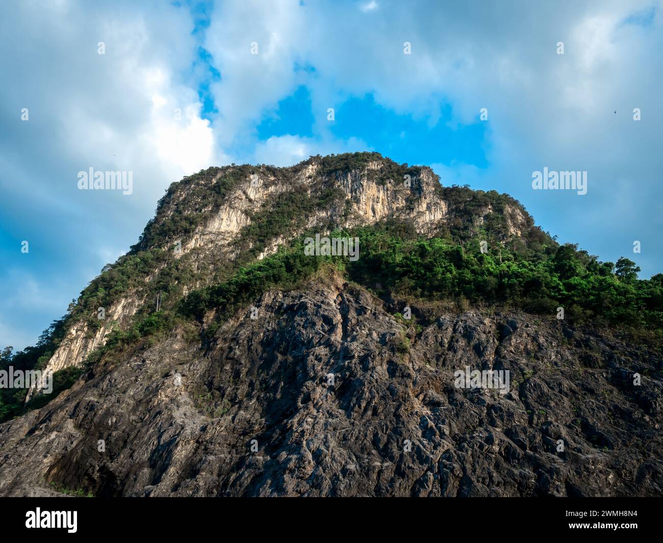Top of beautiful peak rock mountain texture background, view from bottom. Strong cliff on blue sky and cloud backgrounds, nature travel scenery. Old q Stock Photo