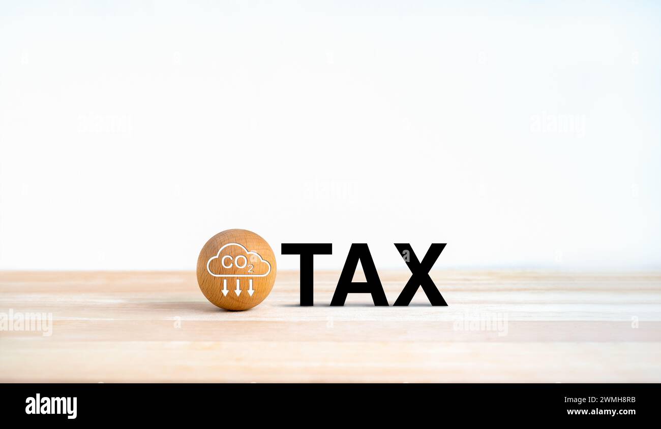 Carbon tax. Carbon emission icon on wood ball with. Black text, TAX on wooden desk and white background with copy space. Environmental, social respons Stock Photo