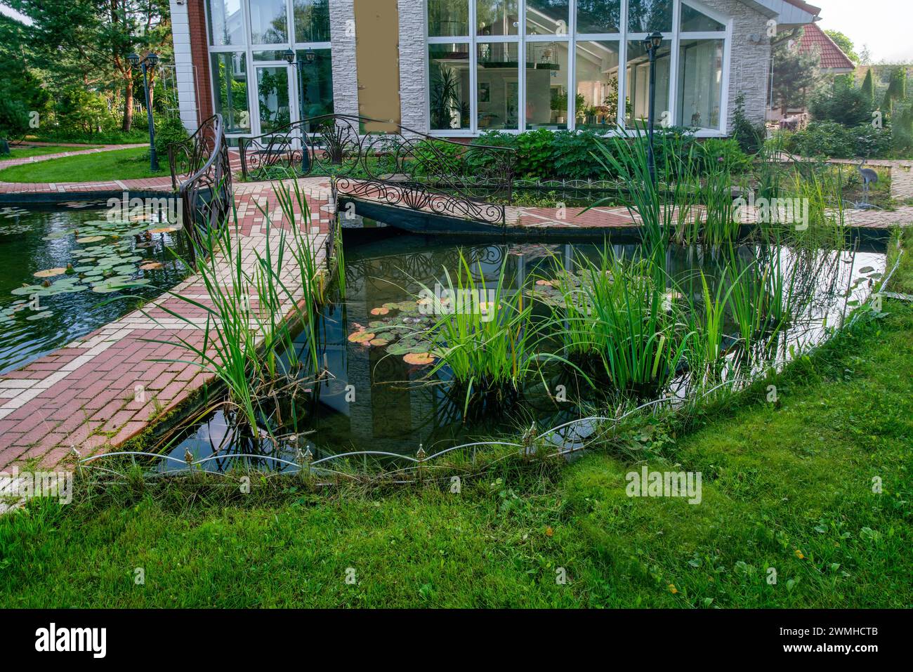 Fantastic Water Garden next to cottage in Moscow Oblast with water plants and small briвпу witg metal railngs Stock Photo