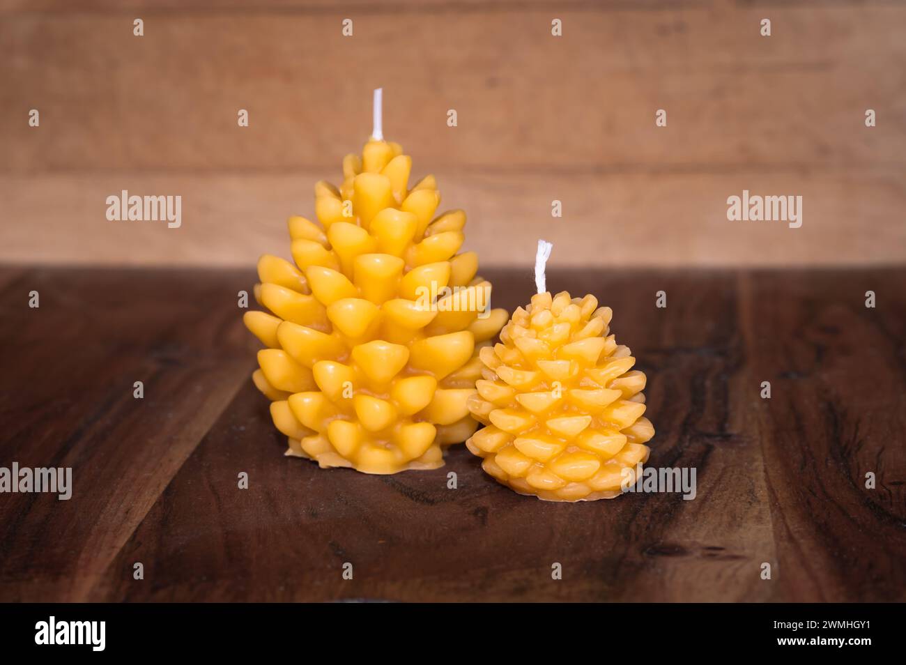 Two bees wax candles shaped like pine cones on wood background Stock Photo