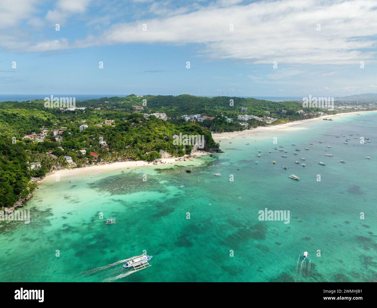 White sand in Diniwid Beach. Boats over clear turquoise water with ...