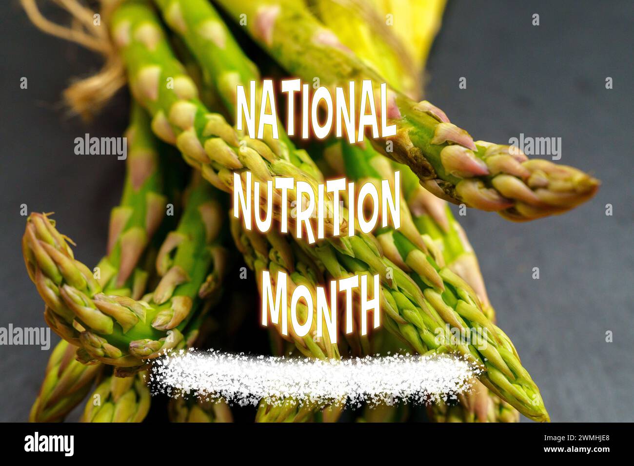 National Nutrition Month, showcasing a bundle of fresh asparagus tied with twine on a slate board, accompanied by colorful text. Stock Photo