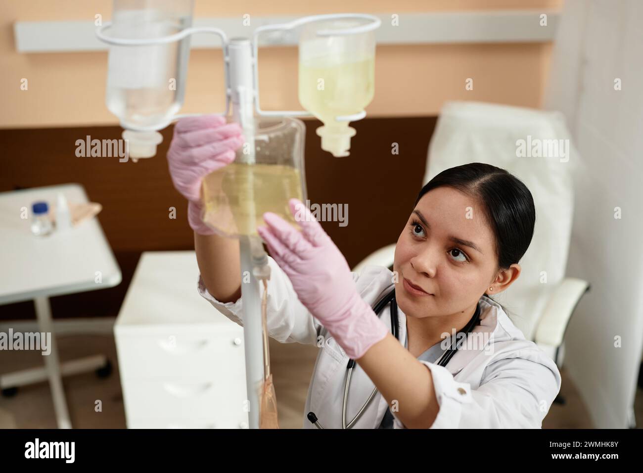 High angle portrait of female nurse setting up equipment for IV drip treatment in procedure room at clinic copy space Stock Photo
