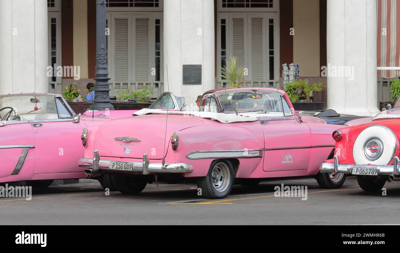020 Pink and red American classic cars -almendron, yank tank Mercury-Chevrolet-Ford- from 1953- stationed on Paseo del Prado promenade. Havana-Cuba. Stock Photo