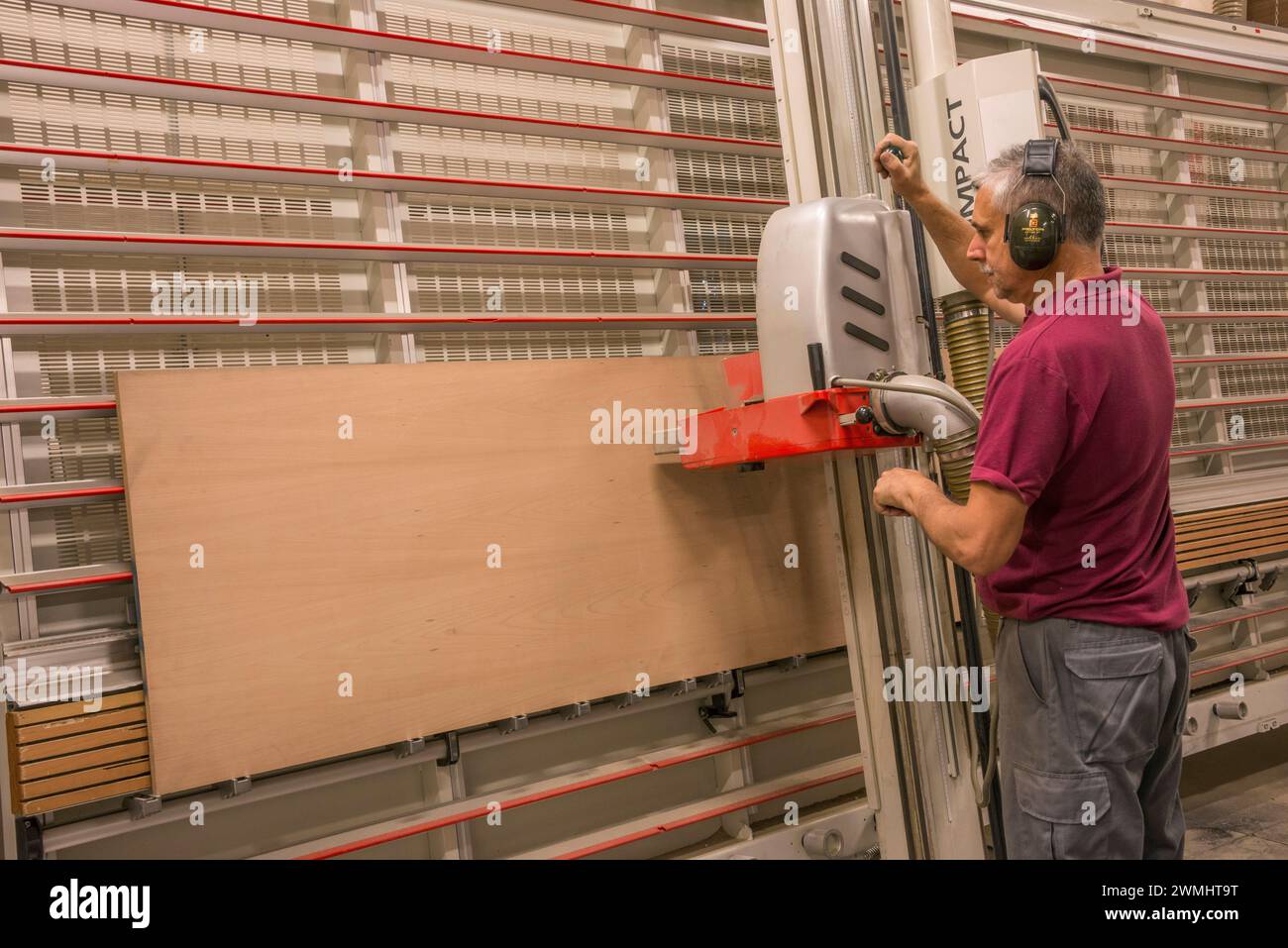 Operator operating a wood cutting machine in an industrial carpentry shop in the Canary Islands Stock Photo